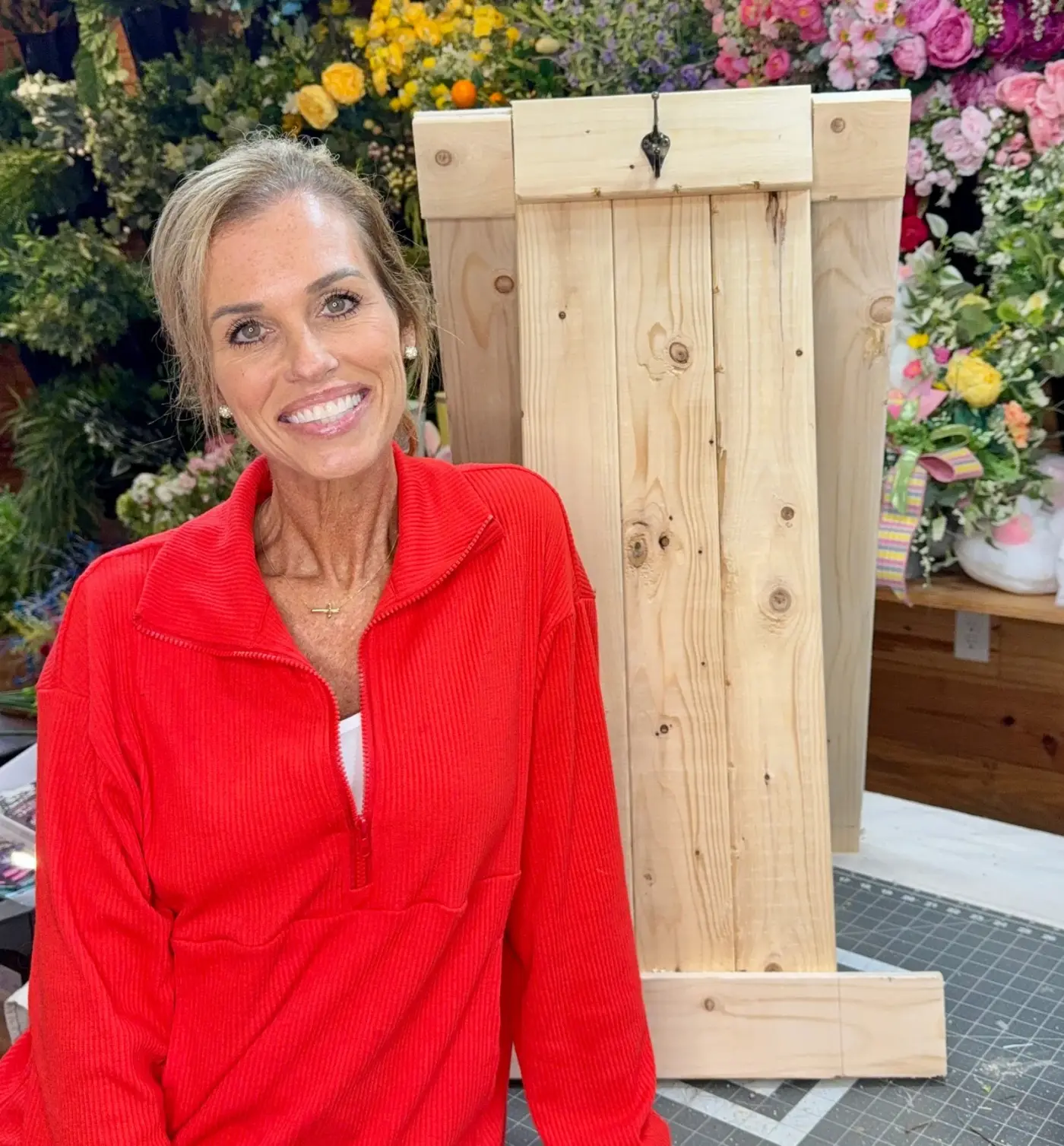 Kandi beside her foldable wooden wreath-making easel in the workshop